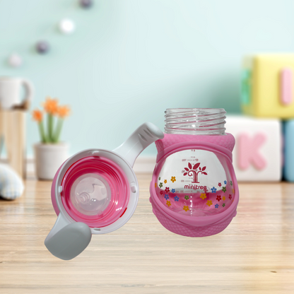 Discover the Minitree Wide Neck Glass Baby Feeder with Handles, perfect for babies 3 months and up. This 160ml feeder, crafted from 0% BPA materials, ensures a safe and healthy feeding experience. Featuring a cute floral print, wide neck for easy cleaning, and ergonomic handles for comfortable grip, it combines practicality, safety, and style. Available now on Babyfairy.pk. Make feeding time delightful and hassle-free!